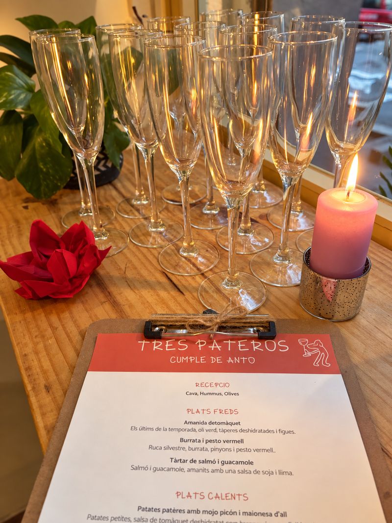 Copas de cava preparadas junto a una vela y un menú impreso de Tres Pateros para una celebración