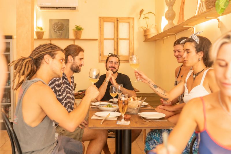 Un grupo de amigos brinda con vino blanco en una mesa del interior cálido de Tres Pateros